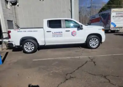 Decal on the right side of a Lanier Custom Homes & Restoration truck with logo on the front door and company name and phone number on the back door in the center