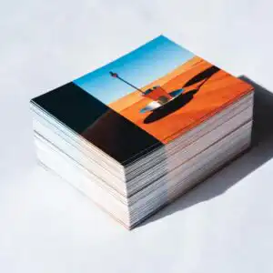 Custom Postcards image with a stack of postcards with a sailboat on the beach at sunset